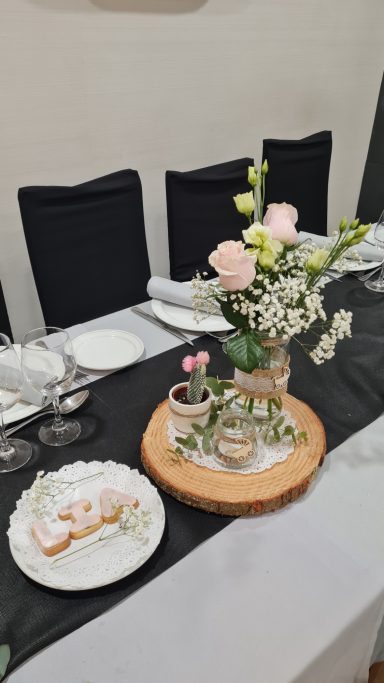 Mesa decorada con flores, platos y dulces para una celebración.